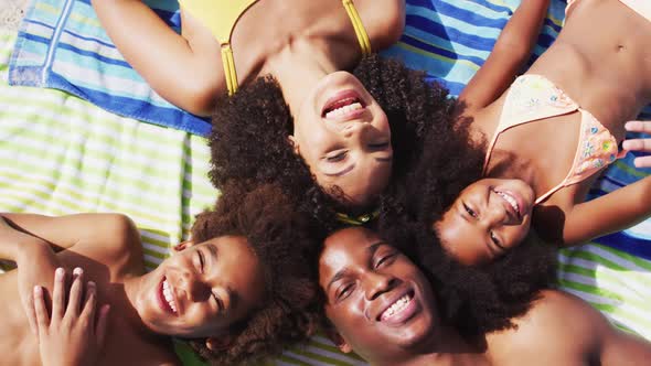 Portrait of african american parents and two children lying on a towel at the beach smiling