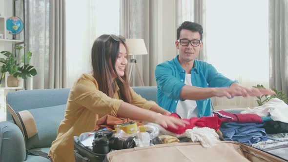 Asian Couple Travelers Packing Clothes In A Suitcase For A New Journey