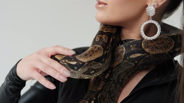 Snake on the Neck of a Woman in a Black Latex Dress on a White Background Slow Motion