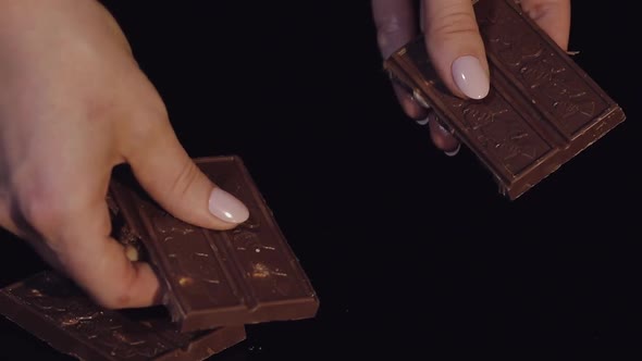 Woman Breaks Black Chocolate Bar with Nuts