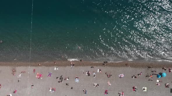 Beautiful coastal city beach with people lying under umbrellas. 