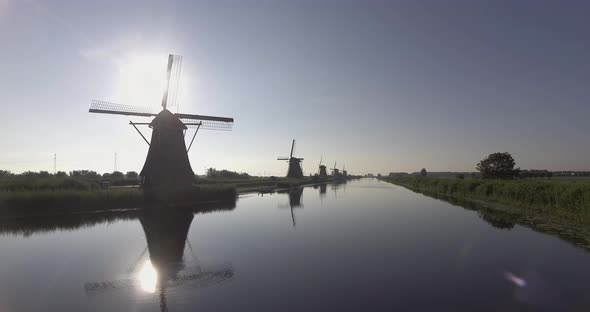 A drone shot panning left, around Dutch Windmills during sunrise