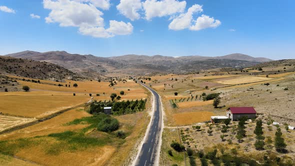 Flying the drone over the road lying between the hills on which there are natural terraces. Above a