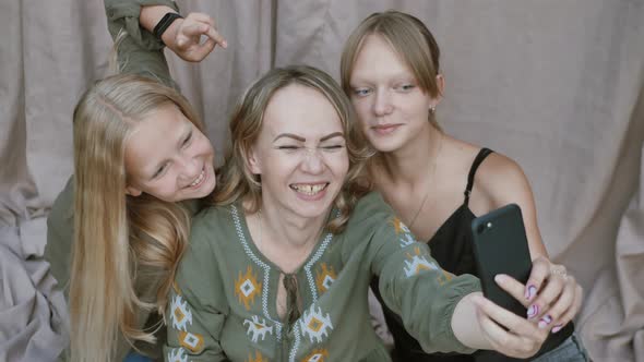 Close Up of Smiling Mother with Daughters Makes Funny Selfies on the Smartphone Grimacing