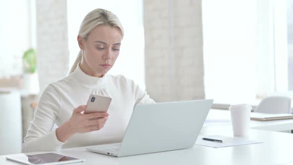 Beautiful Young Businesswoman Using Smartphone and Laptop