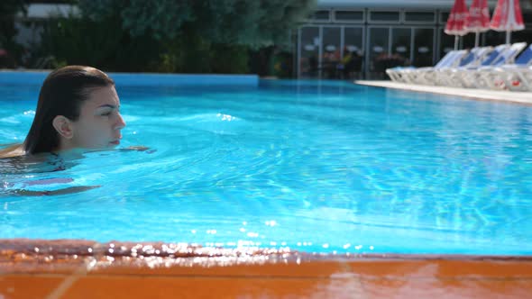 Profile of Attractive Tanned Woman Swimming Through Pool