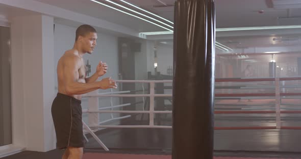 Athletic Man Fighter Trains His Punches, Beats a Punching Bag, Training Day in the Boxing Gym