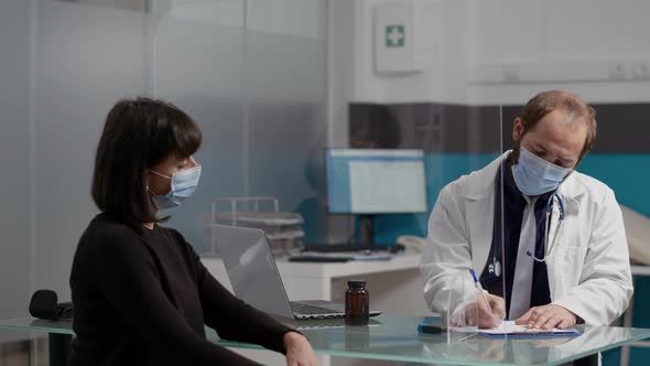 Doctor Taking Notes and Giving Prescription Paper to Female Patient