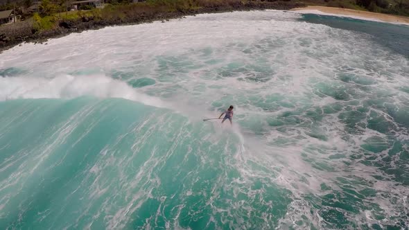 Aerial view of a man sup stand-up paddleboard surfing in Hawaii