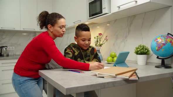 Mother and Son Doing Homework Together By Using Tablet at Home