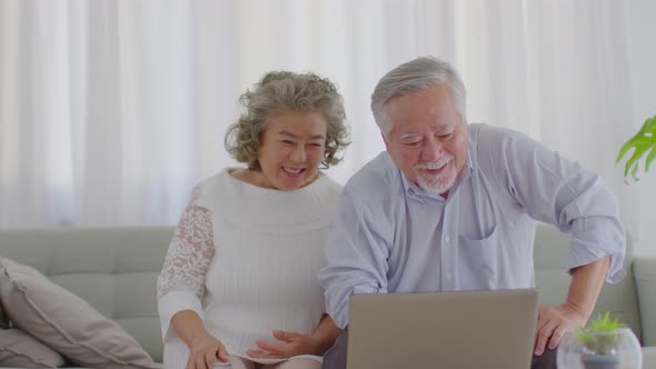 Asian Elderly or Seniors couple with white hairs using computer laptop VDO Conference Call