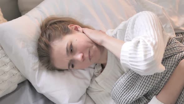 Top View of Young Woman with Neck Pain Lying in Bed