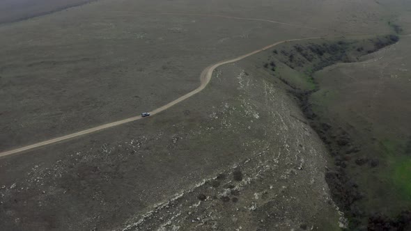 Top View From Above Suv Car Riding on Countryside Road at Hilly Terrain Surrounded By Rocky Meadow