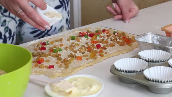A Woman Pours Raisins, Candied Fruits And Almond Flakes Into A Buttered Rolled Dough. Prepares Cruff