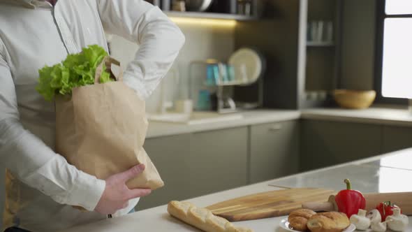 Man Takes Products Out of Paper Bag Bought in Supermarket