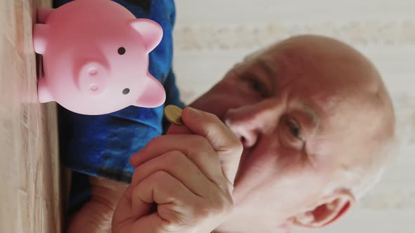 A Senior Caucasian Man Throwing Coin in a Piggy Bank Vertical Slowmo