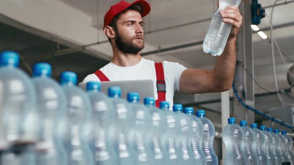 Young Man Worker of Water Factory Checking Quality and Making Inspection in Line Production