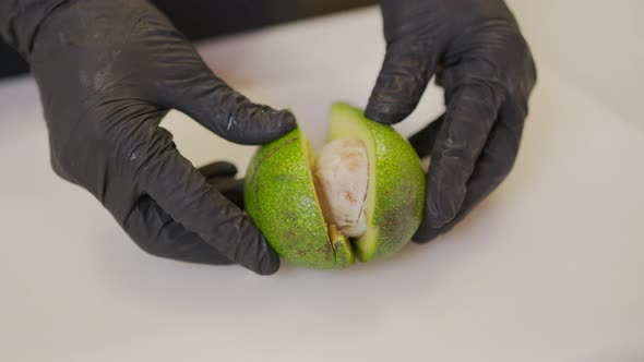 Chef Cuts Skin of Ripe Green Avocado with Vegetable Cutter Make Salad of Vegetables and Fruits and