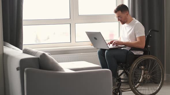 Young Man in Wheelchair Using Laptop Working at Home
