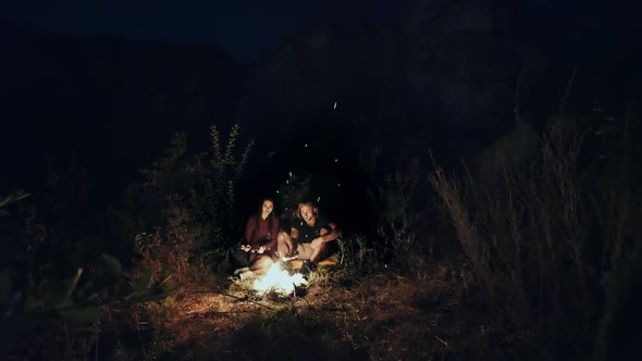 Young Couple of Campers Sitting Around a Campfire