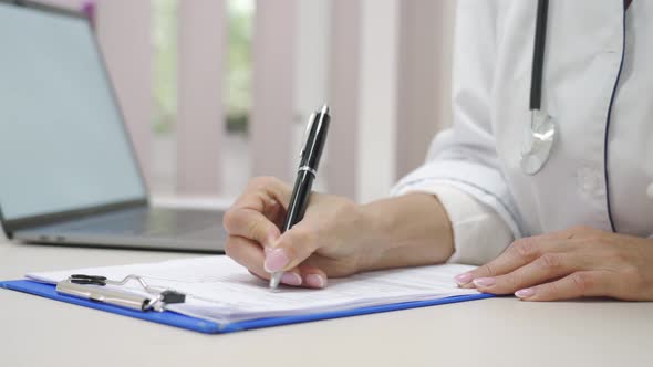 Closeup Female Doctor Hands Taking Notes and Filling Medical Questionnaire