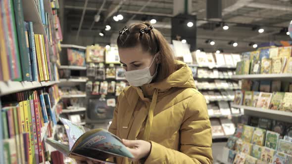Woman in Protective Medical Mask Chooses Books at Supermarket During Covid19 Coronavirus Epidemic