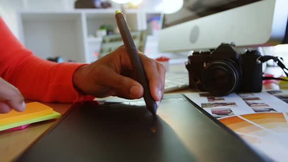 Mid section of female fashion designer using graphic tablet at desk in office 4k