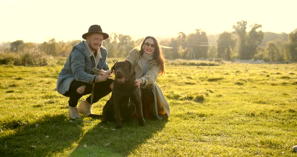 Stylish Modern Couple with a Dog on Meadow