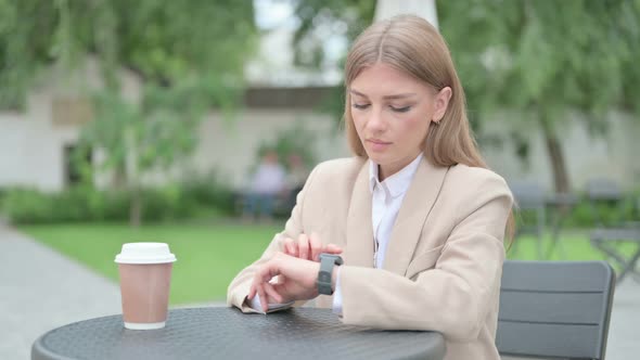 Young Businesswoman with Coffee Using Smart Watch in Outdoor Cafe