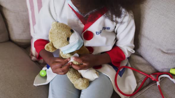 African american girl playing doctor and patient with her teddy bear