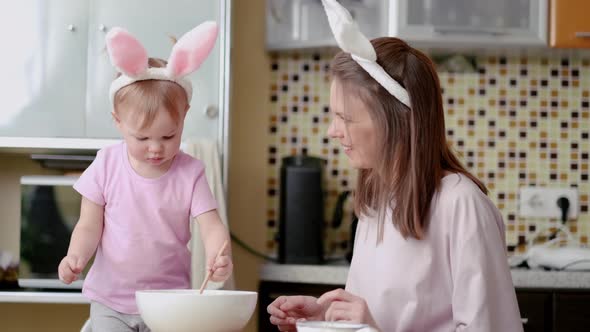 Happy Easter Joyful Family Mom and Daughter Wearing Bunny Ears Headbands Gathering at Table in