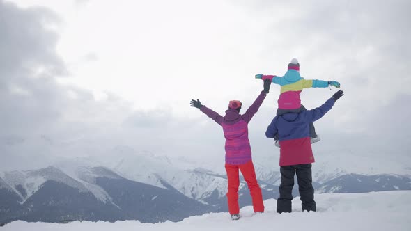 Happy Family Enjoying Winter Vacations in Mountains. Family Ski Vacation. People Observing Mountain