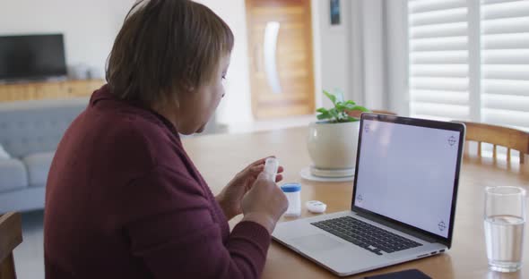 African american senior woman making laptop video call and holding medication, copy space on screen