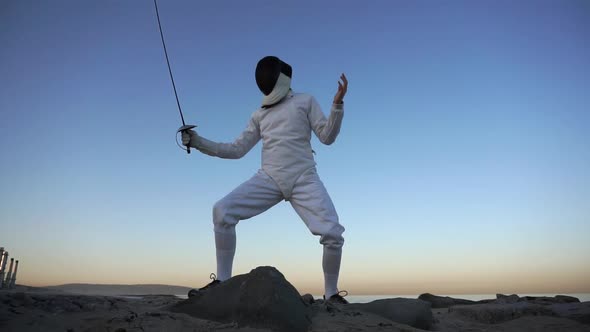 A man and woman fencing on the beach.