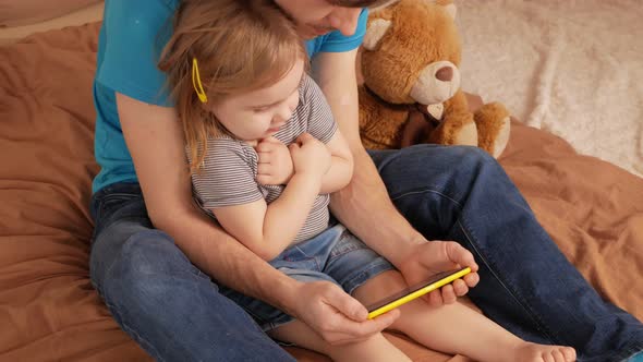 Father and Daughter Watch Cartoon on Phone Home Interior Training