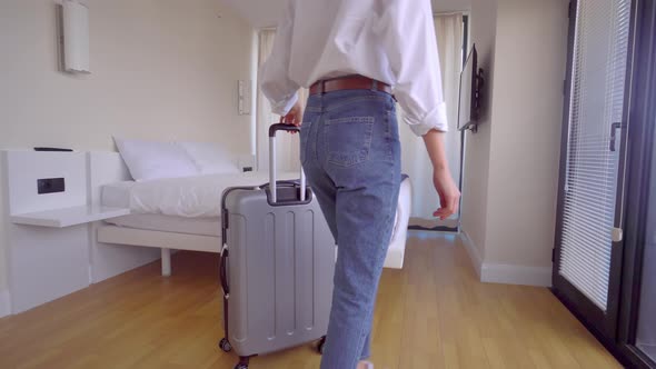 tourist enters apartment with suitcase on , pushes curtains and enjoys view