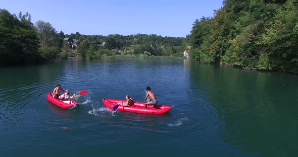 Four young friends paddling canoe and splashing each other with water