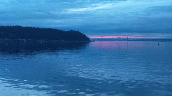 On the bow of the Bremerton Seattle Ferry during the blue sunrise hour, calm water, golden glow in t