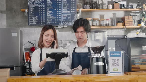 barista woman coffee maker receive phone call and record pre order to computer in coffee cafe shop