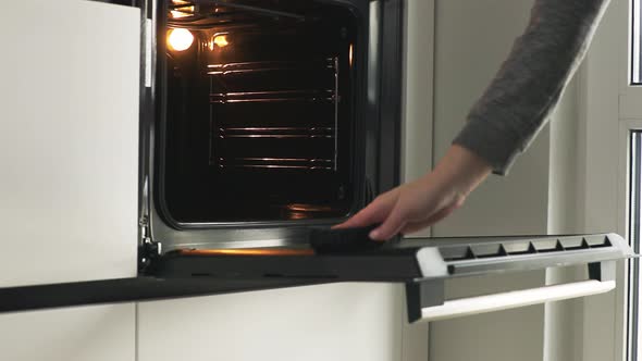 Woman Cleaning Electric Oven After Cooking