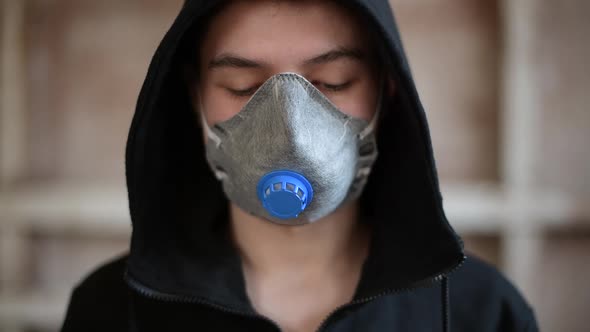 A teenager in a respirator looks down, then raises his eyes