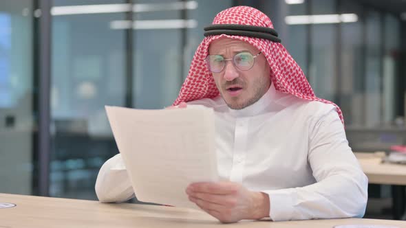 Middle Aged Arab Man Reacting to Loss While Reading  Documents