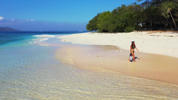 Beautiful ladies tan on luxury coastline beach wildlife by turquoise water with bright sandy backgro