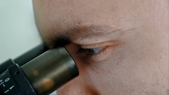 Male Researcher Looking Through Microscope