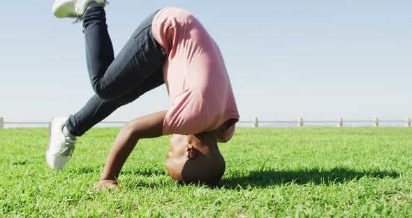 Video of happy african american boy doing rolls on meadow