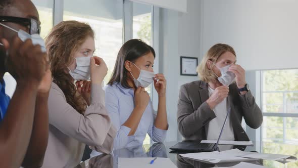 Business People in Face Mask Sitting at Desk During Corporate Meeting in Modern Office