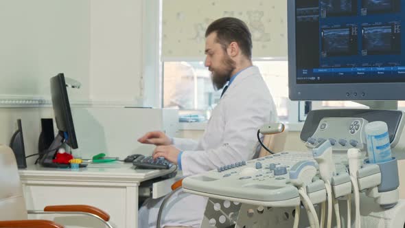 Bearded Doctor Working at His Office Ultrasound Scanner on the Foreground alt
