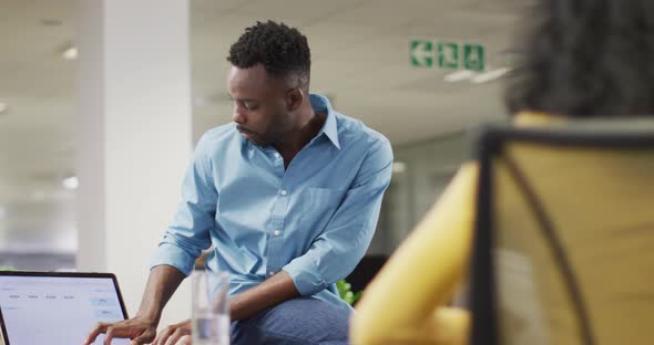 Video of focused african american businessman talking in office with female colleague