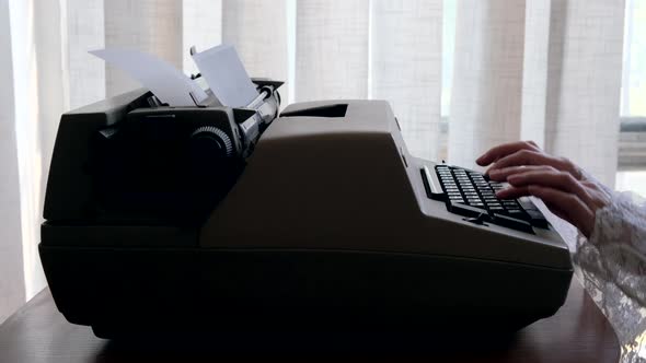 Woman typing on old vintage retro typewriter, fingers press keys