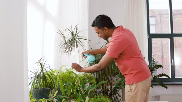 Indian Man Spraying Houseplant with Water at Home